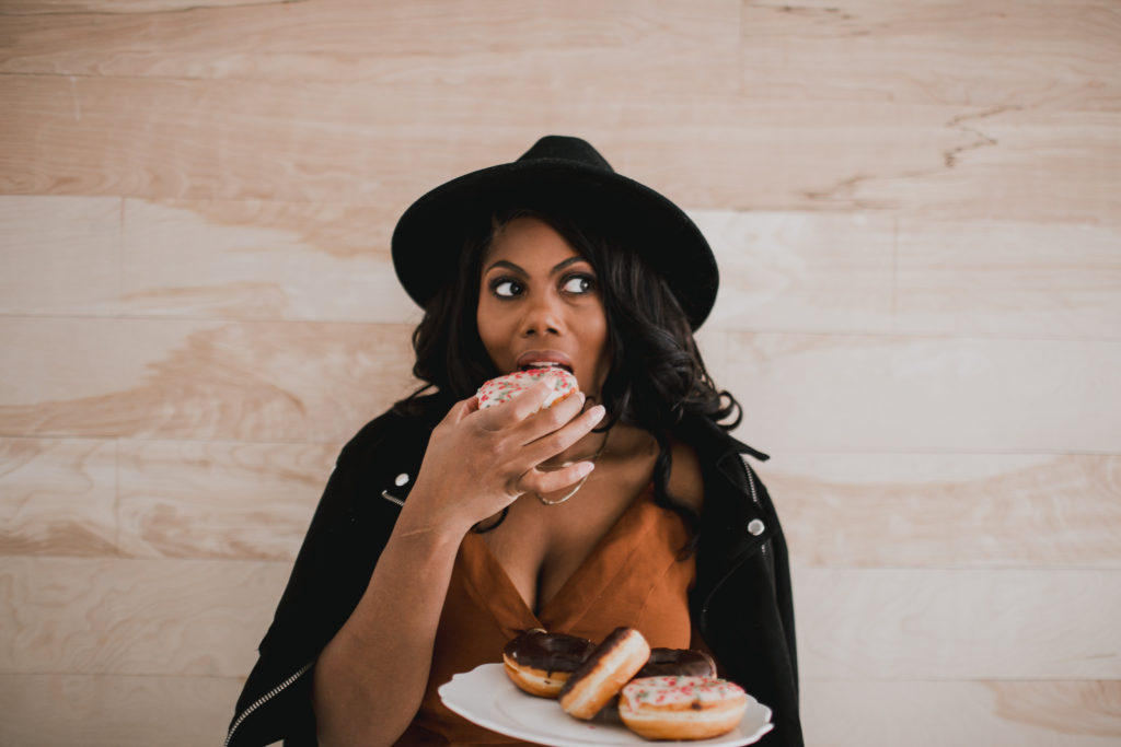Morgan Kelley of Scarlett Events eating donuts in front of light colored wood plank wall
