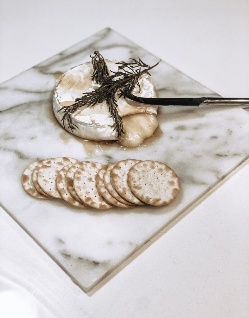 baked brie, rosemary sprigs, water crackers, silver knife, marble cheese plate