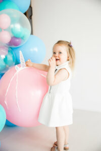 little blonde girl with unicorn balloon installation